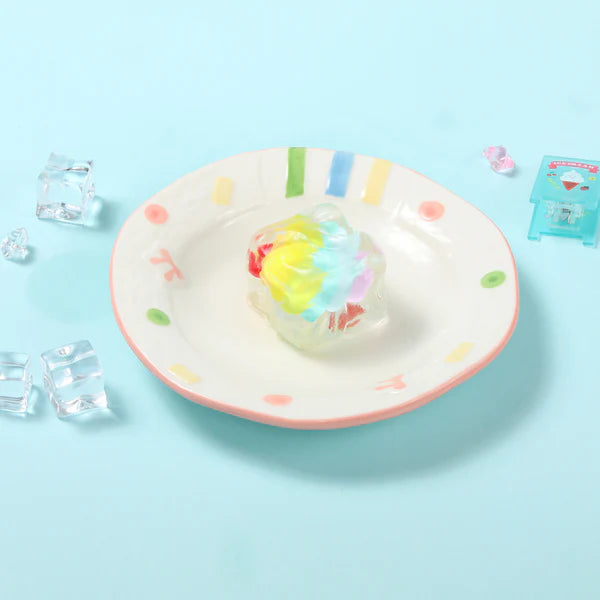 Clear cube with colorful pastel swirls sitting on a white plate with a pink rim