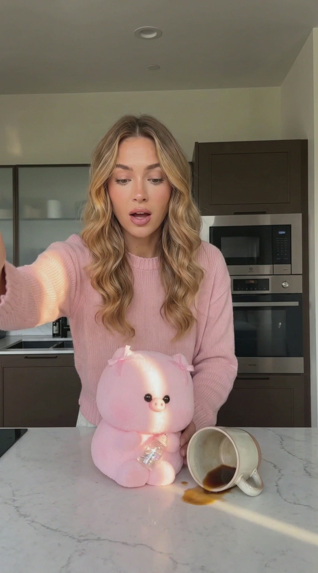 Pink piglet squishy toy being squeezed and slowly rebounding on a pink tabletop with pastel props.